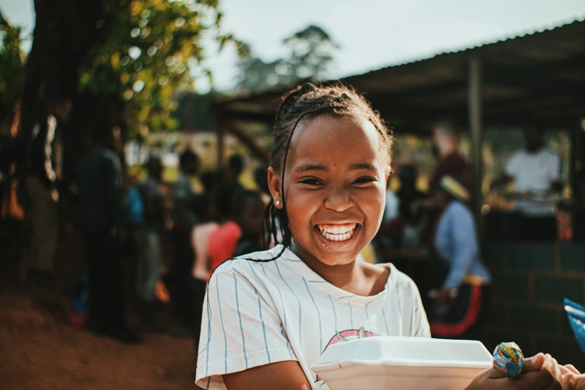 Une élève souriante tenant son repas